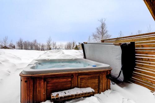 una bañera de hidromasaje en la nieve en Le Haut-Perche - Spa and River View, en Petite-Rivière-Saint-François
