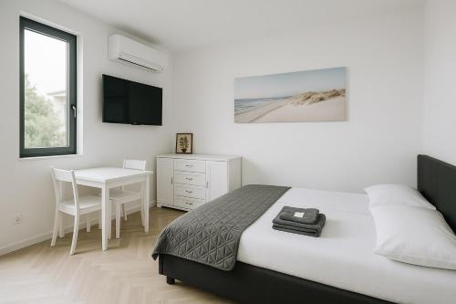 a white bedroom with a bed and a desk at Apartment Anna-Nikola Igalo in Igalo
