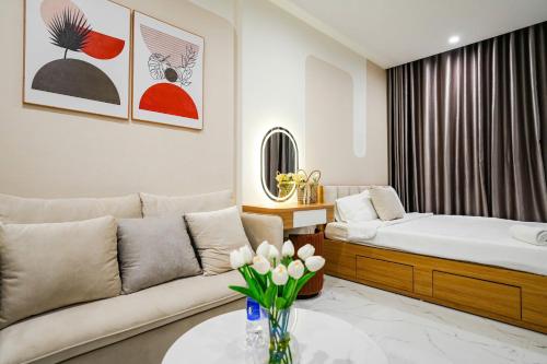a living room with a couch and a table with flowers at CĂN HỘ VINHOMES GRAND PARK QUẬN 9 Studio in Gò Công