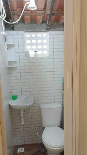 a white bathroom with a toilet and a sink at Pousada Angelical in Saquarema