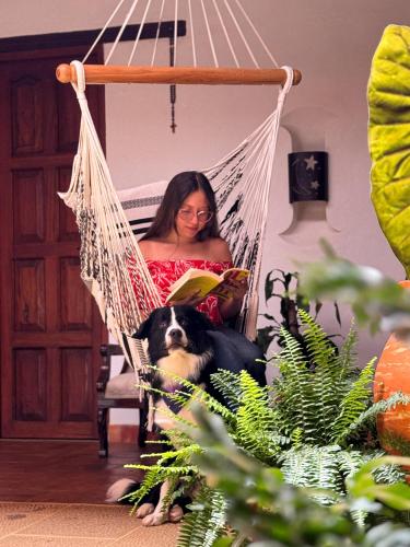 a woman sitting in a hammock with a dog at Hotel Palais Barichara in Barichara