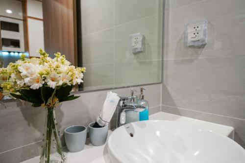 a bathroom with a sink and a vase of flowers at CĂN HỘ VINHOMES GRAND PARK QUẬN 9 Studio in Gò Công