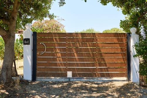 a wooden fence with a gate next to a tree at Ephagros Cretan Countryside House in Dionisi in Dyonisio