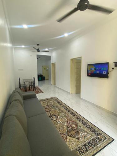 a living room with a couch and a tv on a wall at WIDADD HOMESTAY Kuala Selangor in Kuala Selangor
