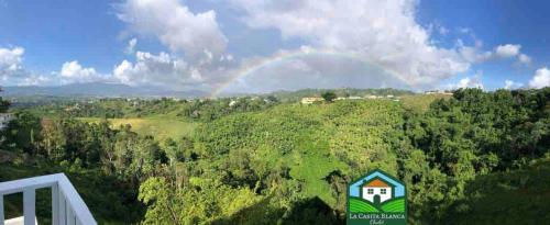 a rainbow in the sky over a hill with trees at La Casita Blanca Chalet Incredible View Romantic in San Lorenzo
