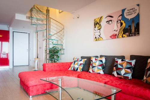 a living room with a red couch and a glass table at Portopiccolo Avolare Apartment InRed - beach included in Sistiana