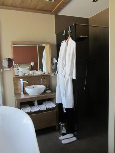 a bathroom with a sink and a white robe on a refrigerator at Le relais des deux tours in Brémondans
