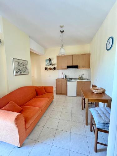 a living room with an orange couch and a kitchen at Nomads in the south in Tsoútsouros