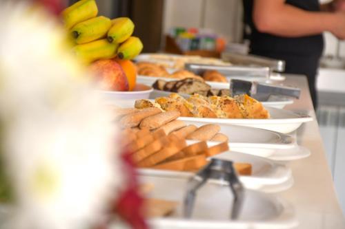 a buffet line with plates of food and fruit at Hotel Euzko Alkartasuna in Macachín
