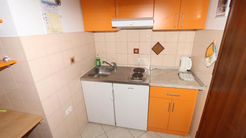 eine kleine Küche mit orangefarbenen Schränken und einem Waschbecken in der Unterkunft Dugiš studio-no parking in Makarska