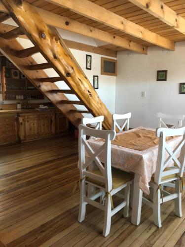a dining room with a table and chairs and a staircase at La Joaquina, Casa de montaña. in El Chalten