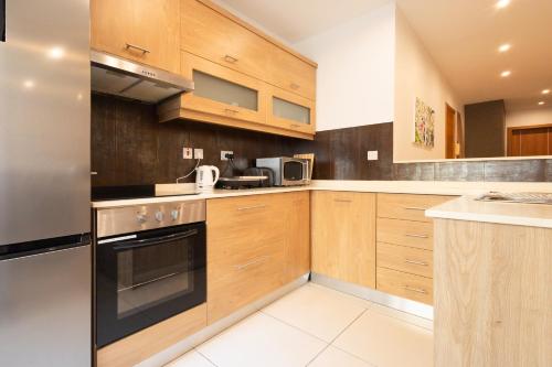 a kitchen with wooden cabinets and a stove top oven at Modern&quiet twin room with shared bathroom in Sliema