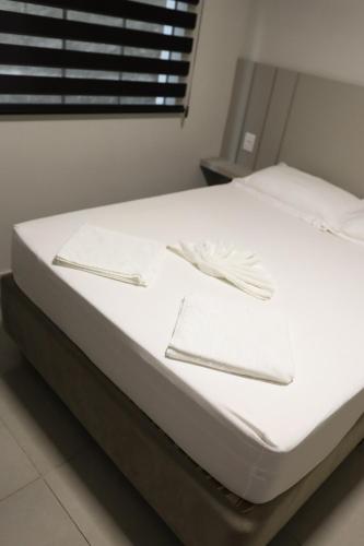 a bed with white sheets and utensils on it at Lou Suítes - Suíte 05 - Essência do Silêncio in Guarapuava