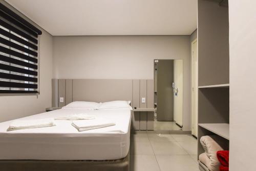 a bedroom with a white bed in a room at Lou Suítes - Suíte 05 - Essência do Silêncio in Guarapuava