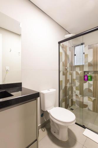 a bathroom with a toilet and a glass shower at Lou Suítes - Suíte 05 - Essência do Silêncio in Guarapuava