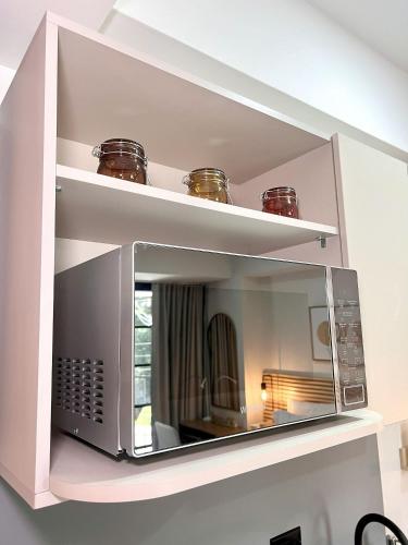 a microwave on a shelf in a room at BIT by Simple stay in Medellín