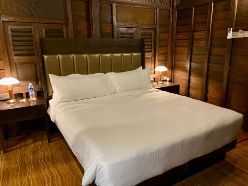 a bedroom with a large white bed with two tables at Landmark Cenang in Pantai Cenang