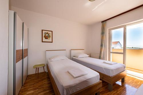 two beds in a room with a window at Apartment Stanka in Novalja