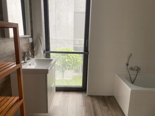 a bathroom with a sink and a tub and a window at Apartament Zoom 42 in Bydgoszcz