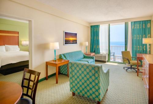 a hotel room with a bed and a room with a bed and a couch at Holiday Inn & Suites Virginia Beach - North Beach by IHG in Virginia Beach