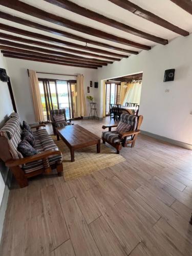 a living room with chairs and a wooden table at Malcom Ocean View Retreat in Pongwe
