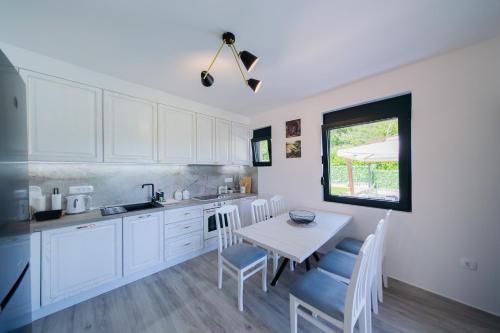 a kitchen with white cabinets and a table and chairs at Villa Goranovic in Herceg-Novi