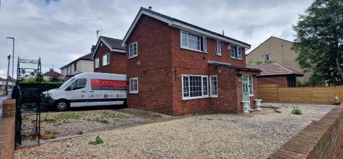 a moving truck parked in front of a brick house at 3-Bed Detached House Private Drive for Two Cars in Farsley