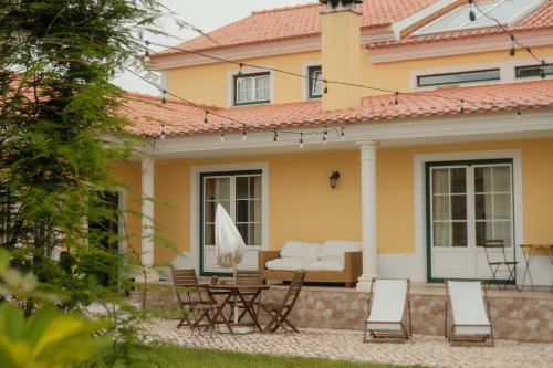 a house with a patio with chairs and a couch at Quinta Amarela - B&B in Nazaré