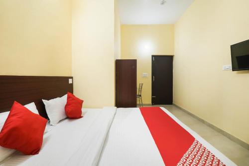 a bedroom with a bed with red pillows and a tv at Hotel O Laavin Inn Near Gomti Riverfront Park in Lucknow
