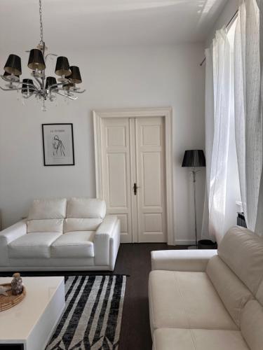a white living room with white furniture and a chandelier at Flanatika Residence Pula in Pula