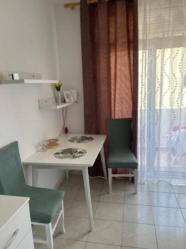 a white table and two green chairs in a kitchen at Sun&See in Durrës