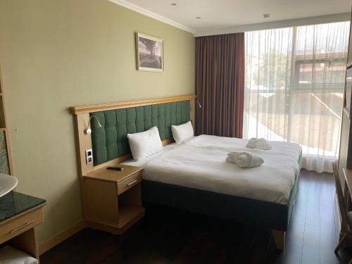 a bedroom with a bed with a green headboard and a window at Arnas hotel in Almaty