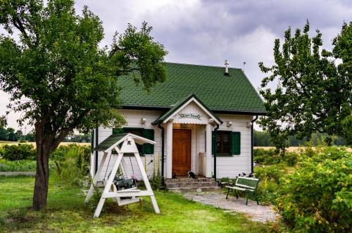 a small white house with a ladder in front of it at Biały Domek w Ogrodzie Różanym 