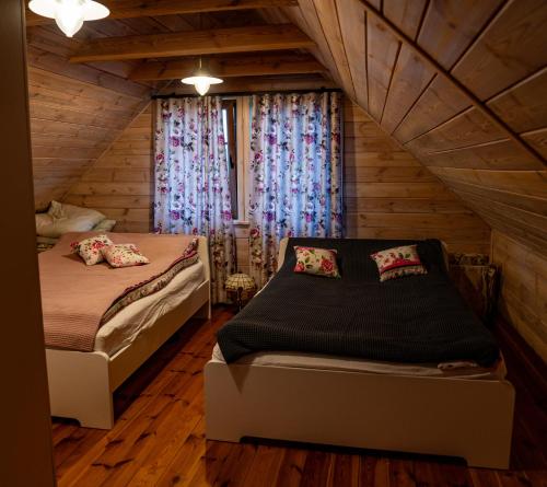 a bedroom with two beds in a log cabin at Biały Domek w Ogrodzie Różanym 