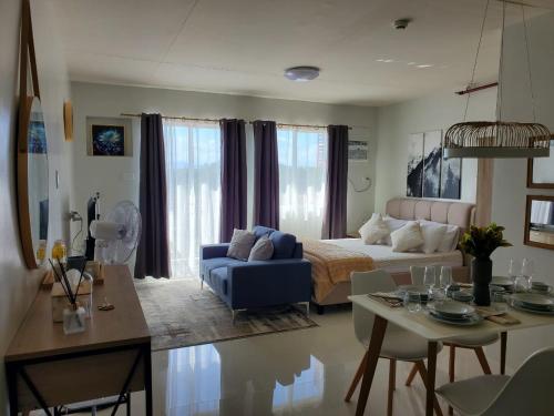 a living room with a bed and a blue couch at VERDANT by Vista Manors Deluxe Rooms with Balcony, Gym and Swimming Pool in Puerto Princesa City