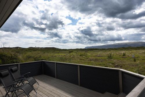 a deck with chairs and a view of a field at Luxury Villa in Golden Circle with hot tub in Selfoss