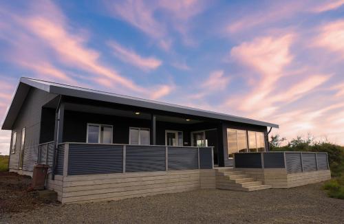 a house with a black roof and a cloudy sky at Luxury Villa in Golden Circle with hot tub in Selfoss