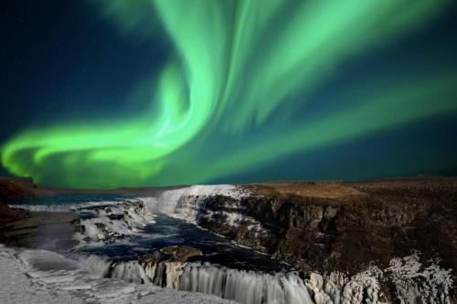 an image of the aurora dancing over a waterfall at Luxury Villa in Golden Circle with hot tub in Selfoss