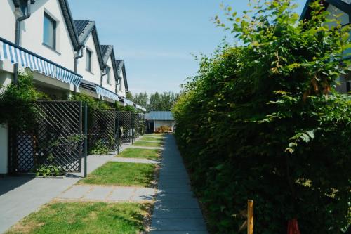 a sidewalk in front of a house with a hedge at Domki Wierzbówka in Mielno