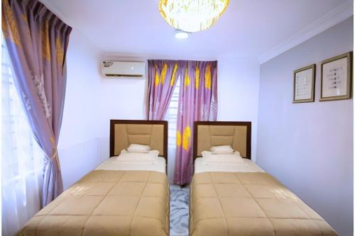 Dos camas en una habitación con ventana. en Chanan Court Apartment, en Accra