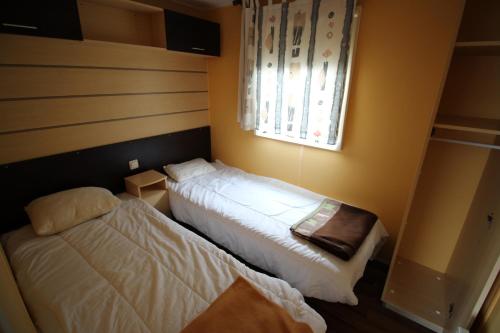 a bedroom with two beds and a window at Land's Hause Bungalows par La Conciergerie Française Emplacement 6AB in Pataias
