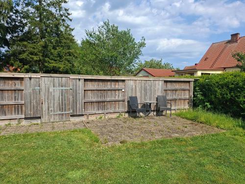 a wooden fence with two chairs in a yard at Privat gästhus med egen trädgård in Kävlinge