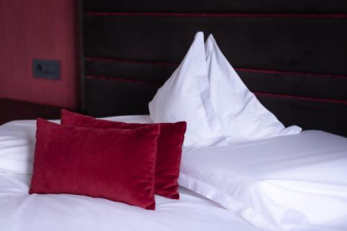 a bed with white sheets and red pillows at The Fifth Floor by Old Town Hotel in Timişoara
