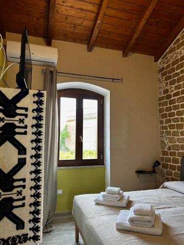 two beds in a room with a window and towels at Casa Gioconda Bed & Breakfast in Nuxis