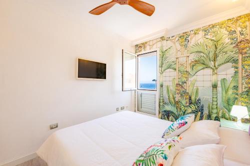 Un dormitorio con una cama blanca con papel pintado tropical. en El Poris, en Porís de Abona
