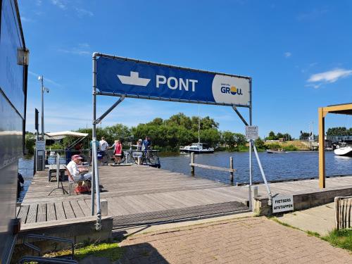 a dock with a sign that reads point at Fries Vakantiehuis, grote tuin, nabij het Pikmeer in Grou