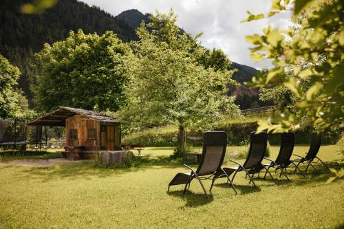 a group of chairs sitting in the grass in a field at Untermairhof Appartment Residence in Selva dei Molini