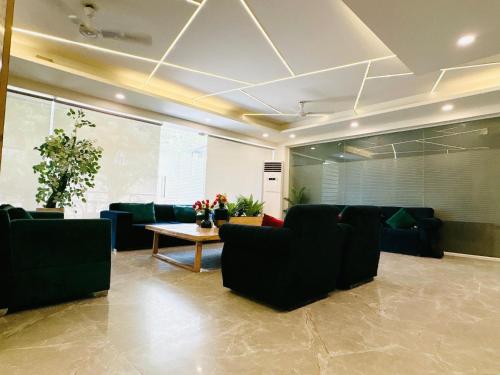 a living room with black couches and a table at Hotel Golf View Sakura & Suites in Gurgaon