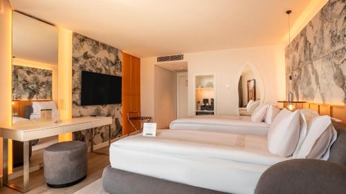 a hotel room with two beds and a desk at Qlusive Hotel in Kusadası