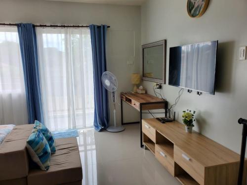 a living room with a flat screen tv and a desk at VERDANT by Vista Manors Deluxe Rooms with Balcony, Gym and Swimming Pool in Puerto Princesa City